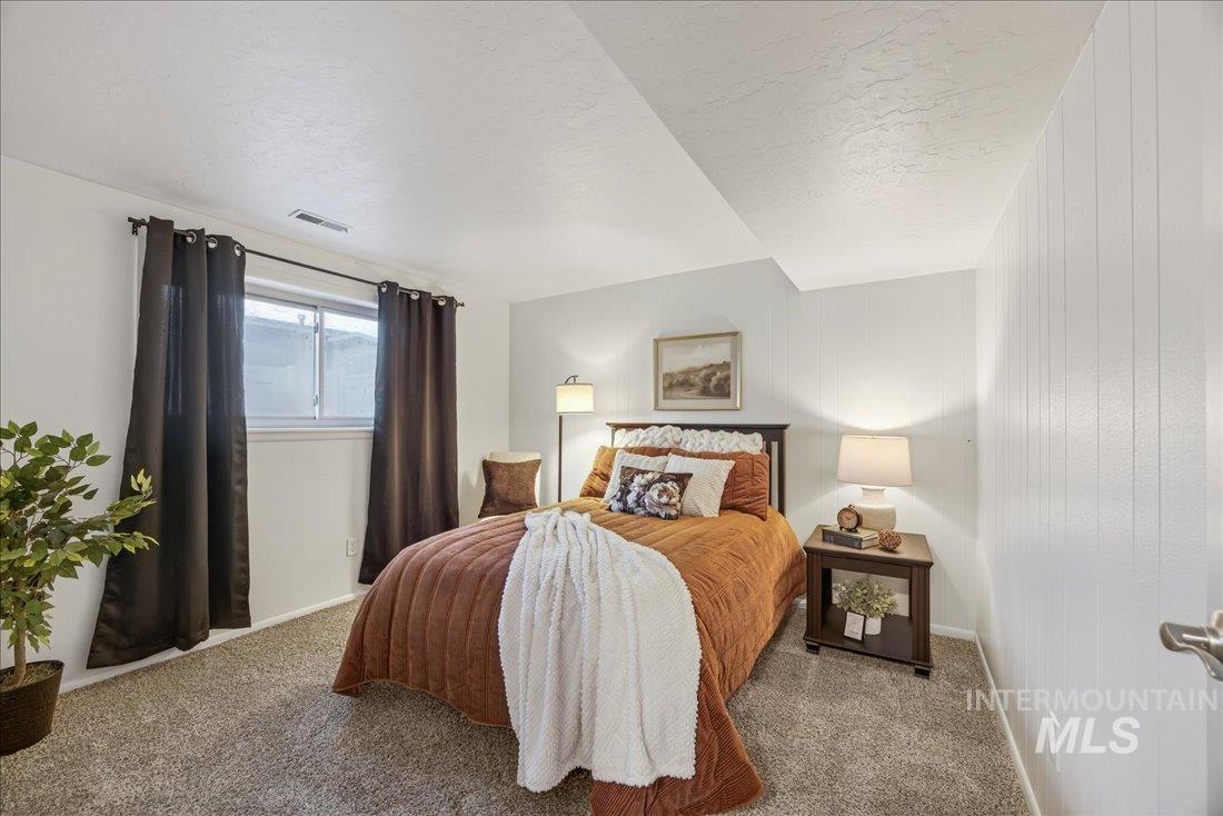 Carpeted bedroom with baseboards and wooden walls