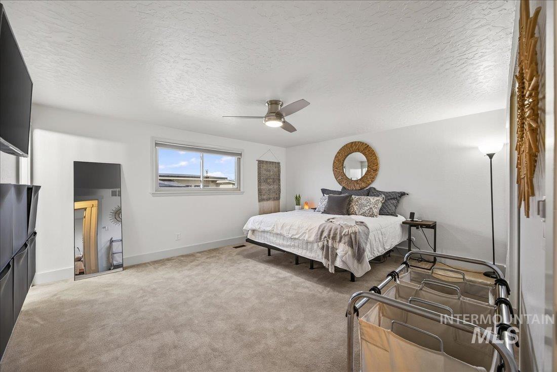 Bedroom with light carpet, a textured ceiling, and ceiling fan