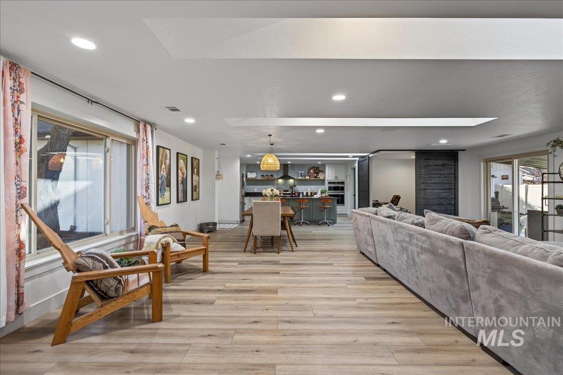 Living room featuring light wood-style floors, a skylight, and recessed lighting