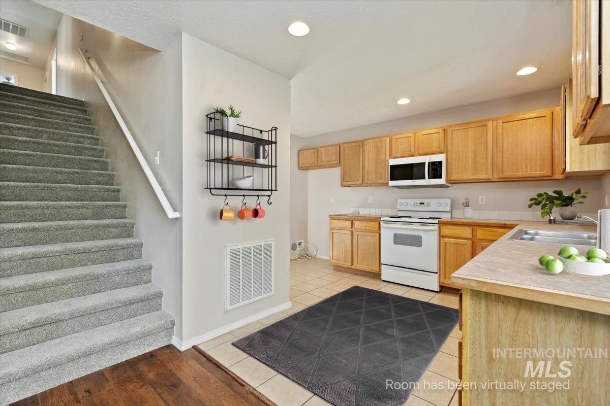 Kitchen featuring light countertops, white appliances, recessed lighting, light brown cabinetry, and light tile patterned floors