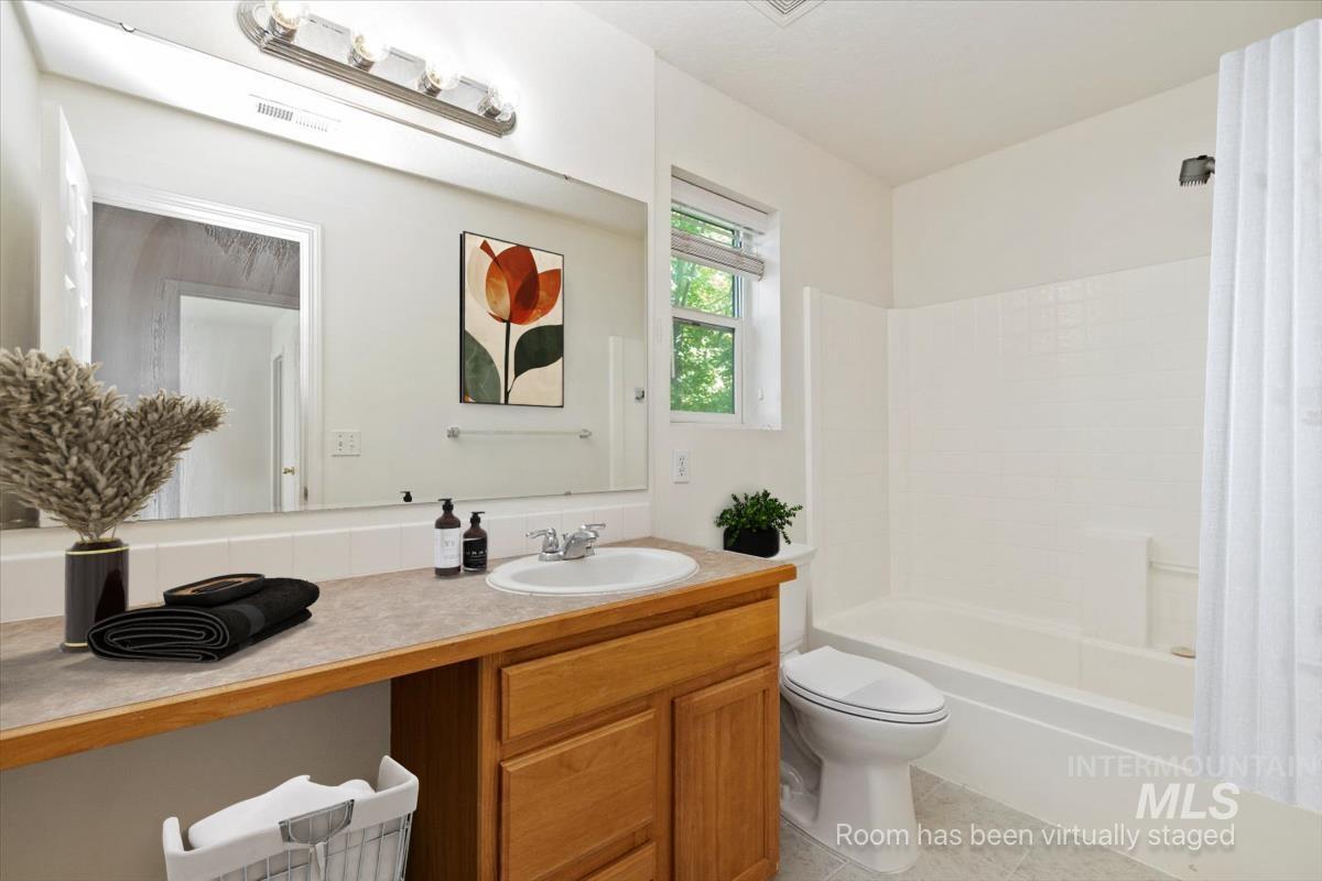 Full bathroom with shower / tub combo, vanity, and light tile patterned flooring