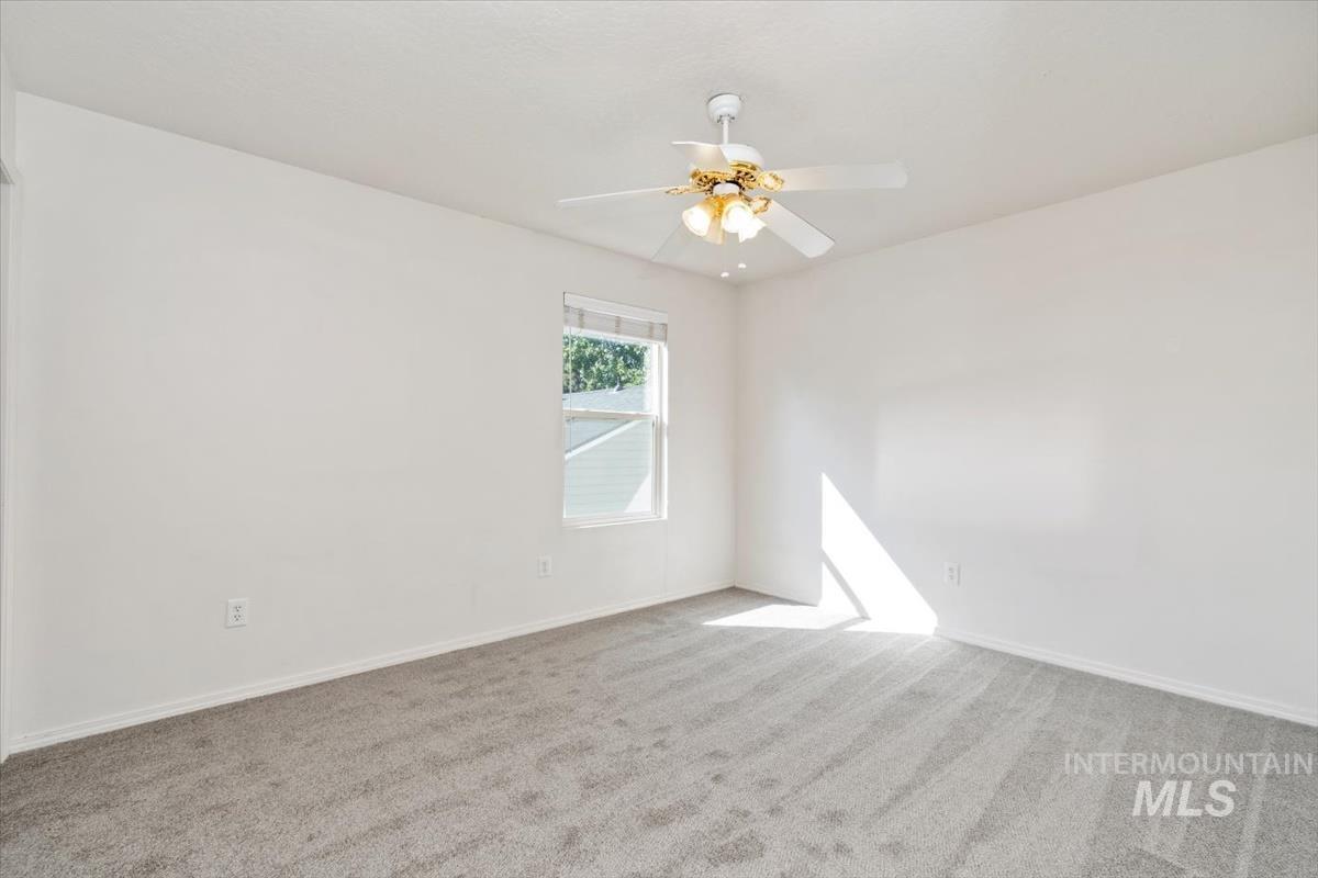 View of front of home featuring an attached garage, concrete driveway, stone siding, and a front yard