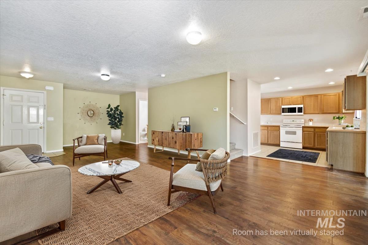 Living area with dark wood-style floors, a textured ceiling, recessed lighting, and stairway