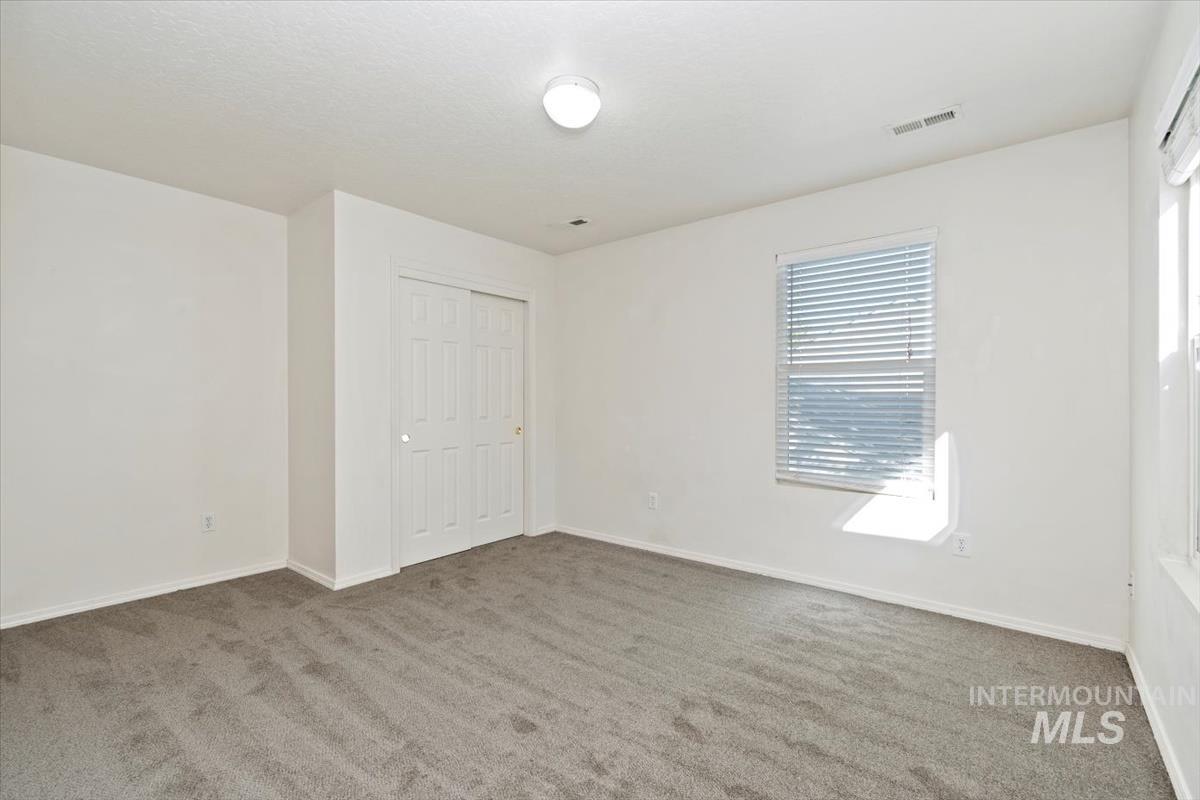 View of front of house featuring a garage, concrete driveway, stone siding, and a front yard