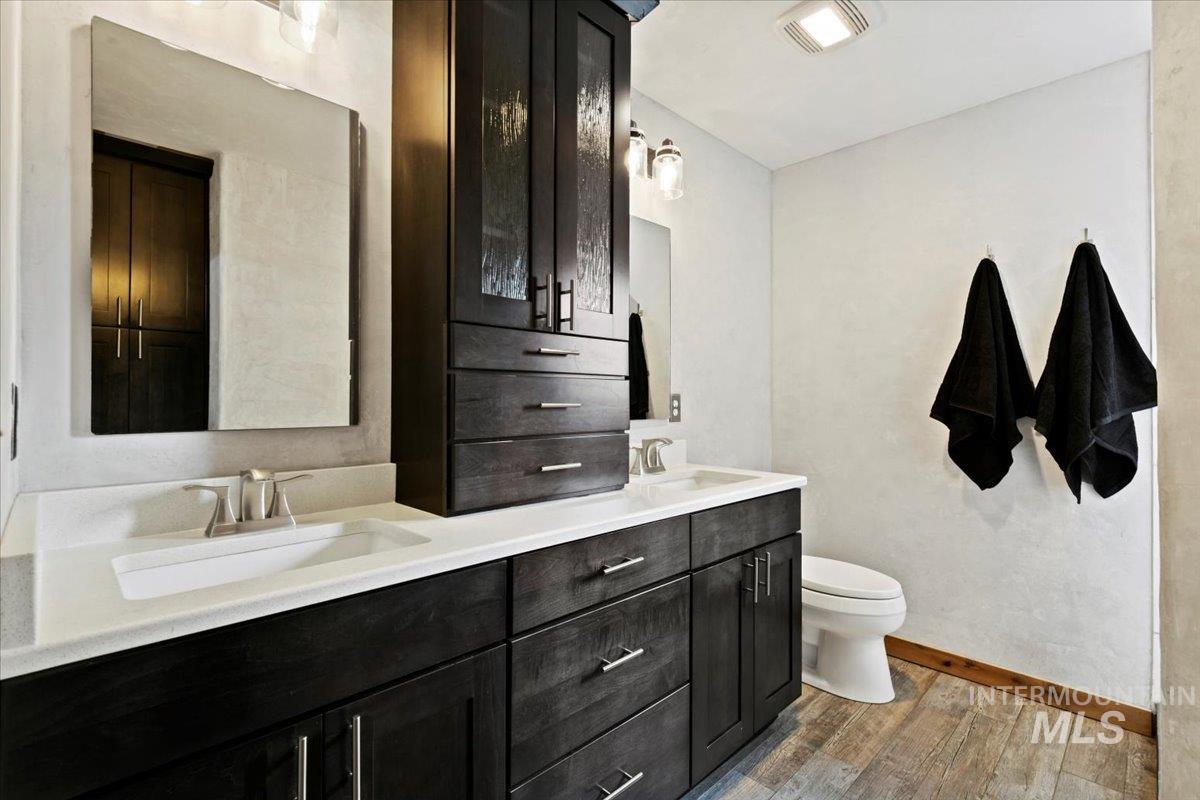 Renovated primary bathroom with beautiful rich cabinetry and quartz counters and walk-in tiled shower
