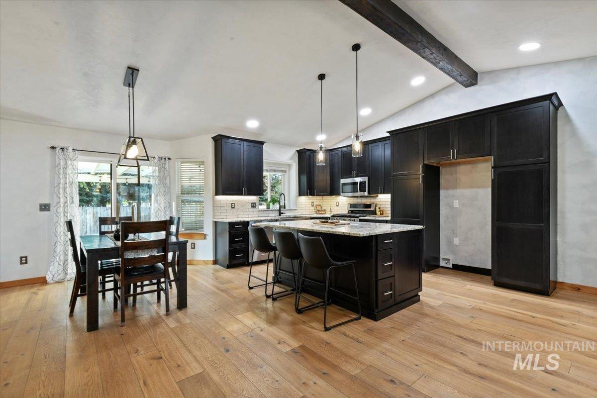 Stunning remodeled kitchen with tasteful backsplash, a breakfast bar, decorative light fixtures, recessed lighting, and granite counters.
