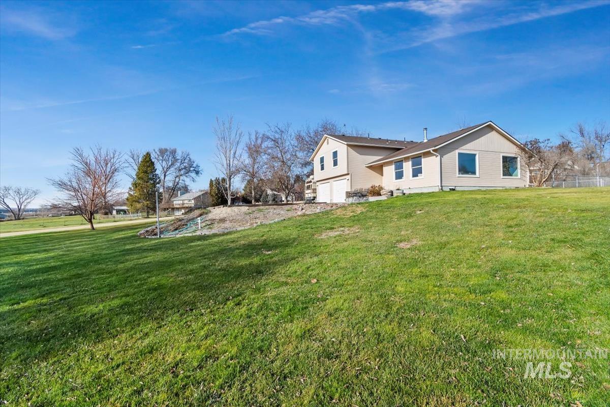 View of home's exterior featuring a large green space and an attached garage