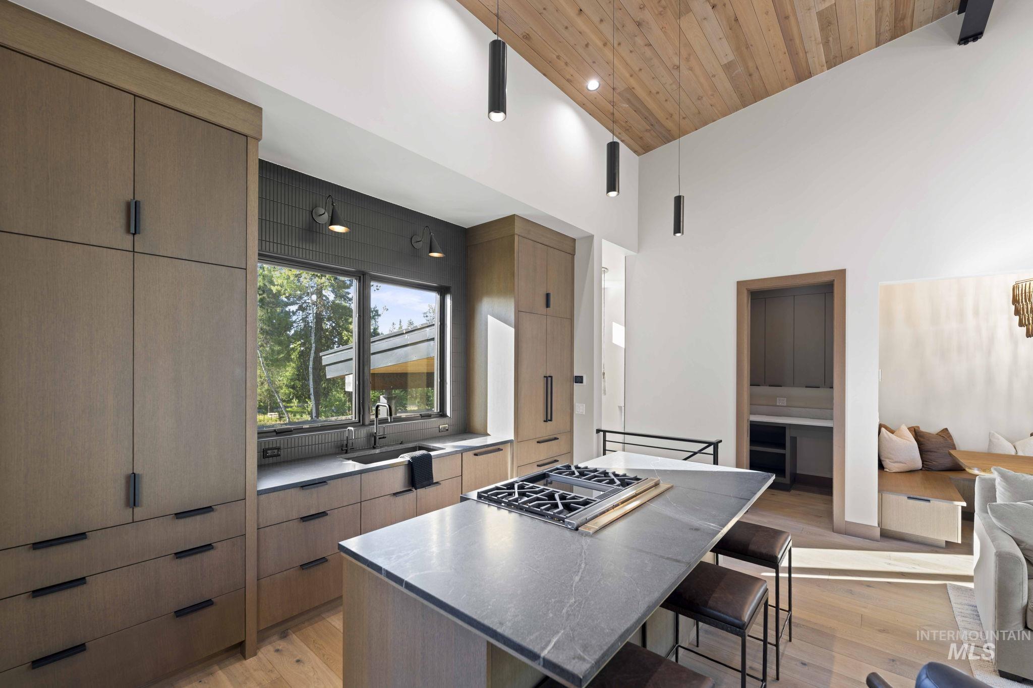 Kitchen featuring light wood-style floors, high vaulted ceiling, a kitchen breakfast bar, modern cabinets, and wood ceiling