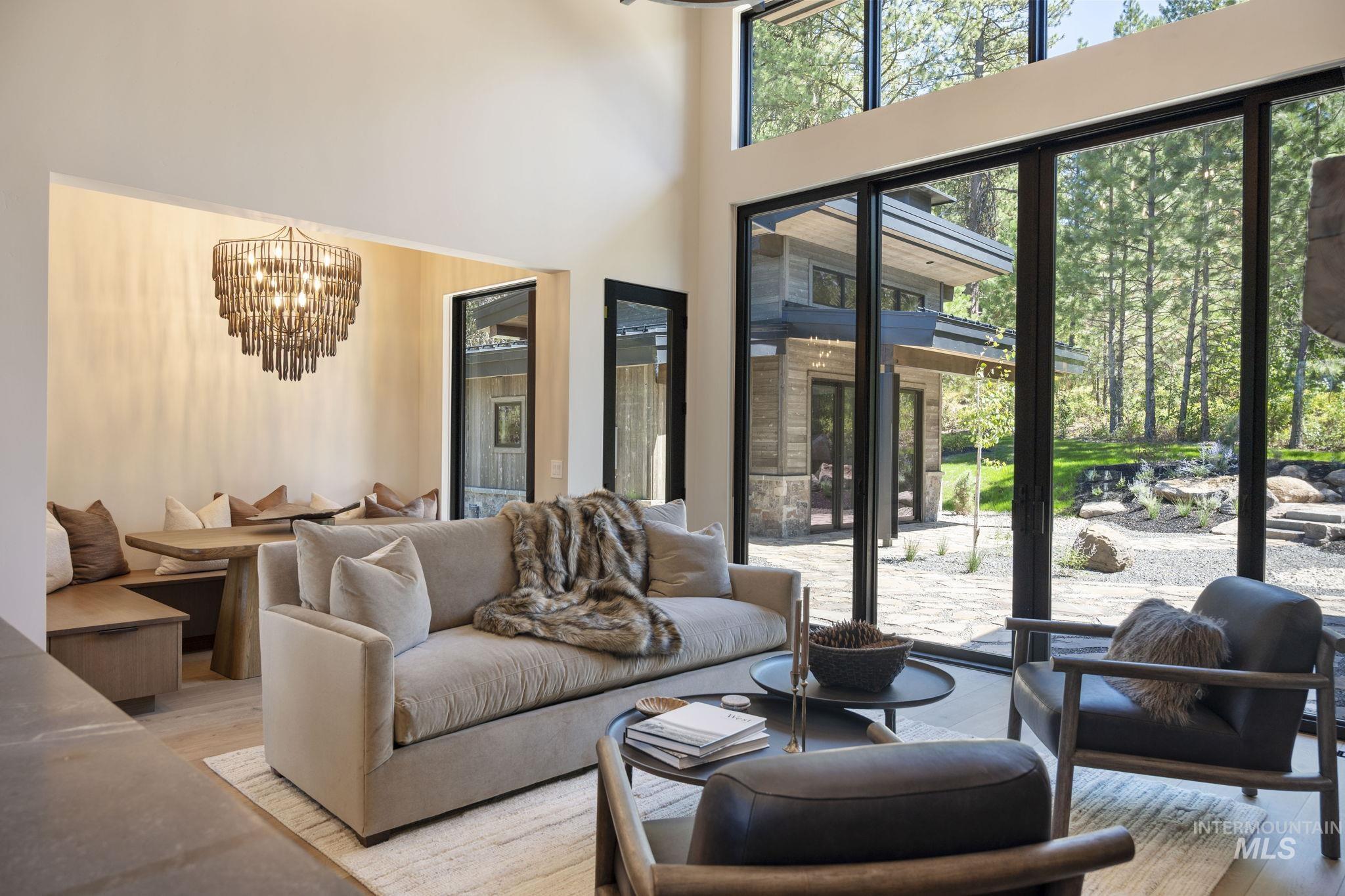 Living area featuring a chandelier, light wood-type flooring, healthy amount of natural light, and a towering ceiling
