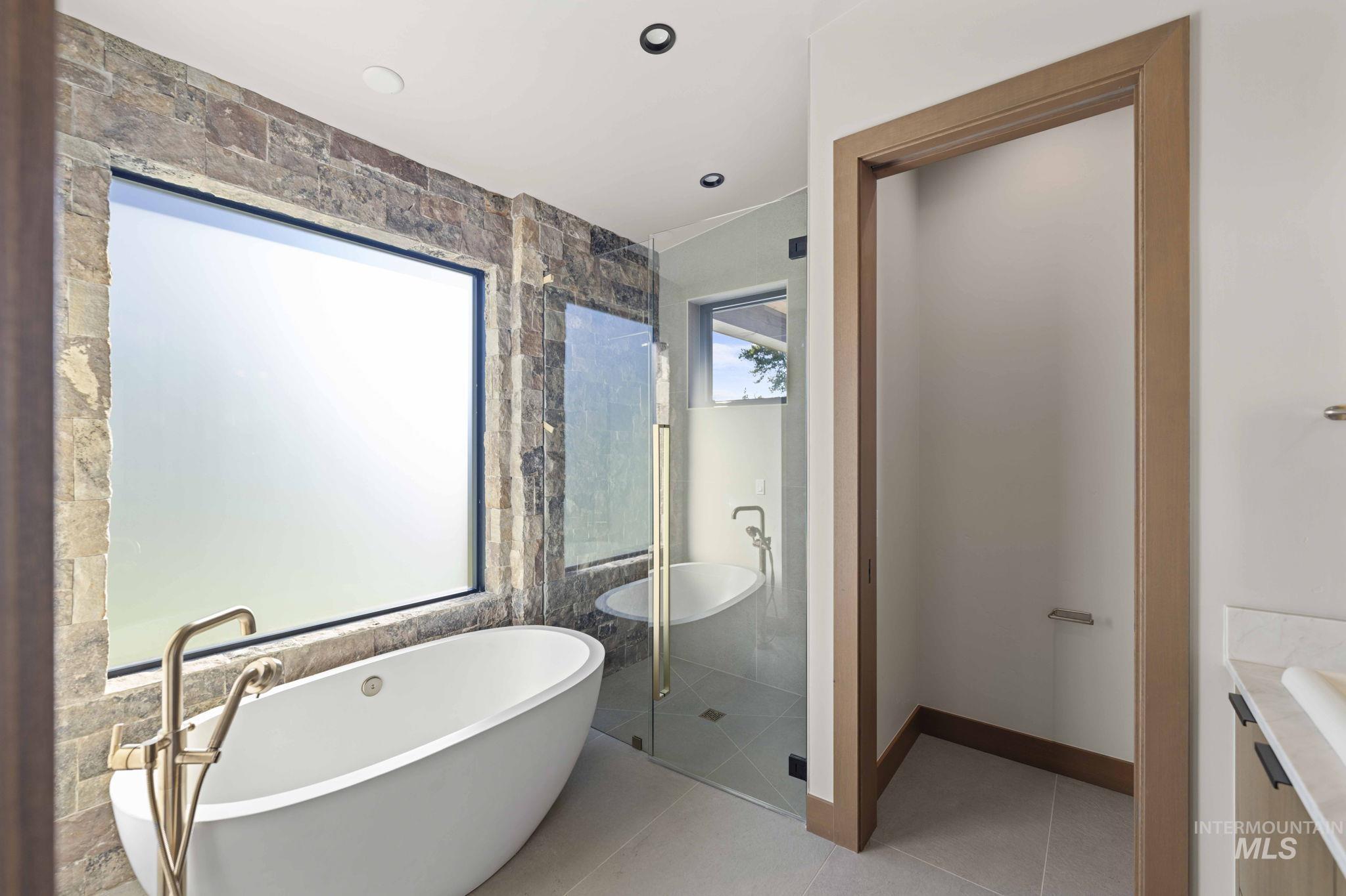 Bathroom featuring a freestanding tub, vanity, light tile patterned flooring, a shower stall, and recessed lighting