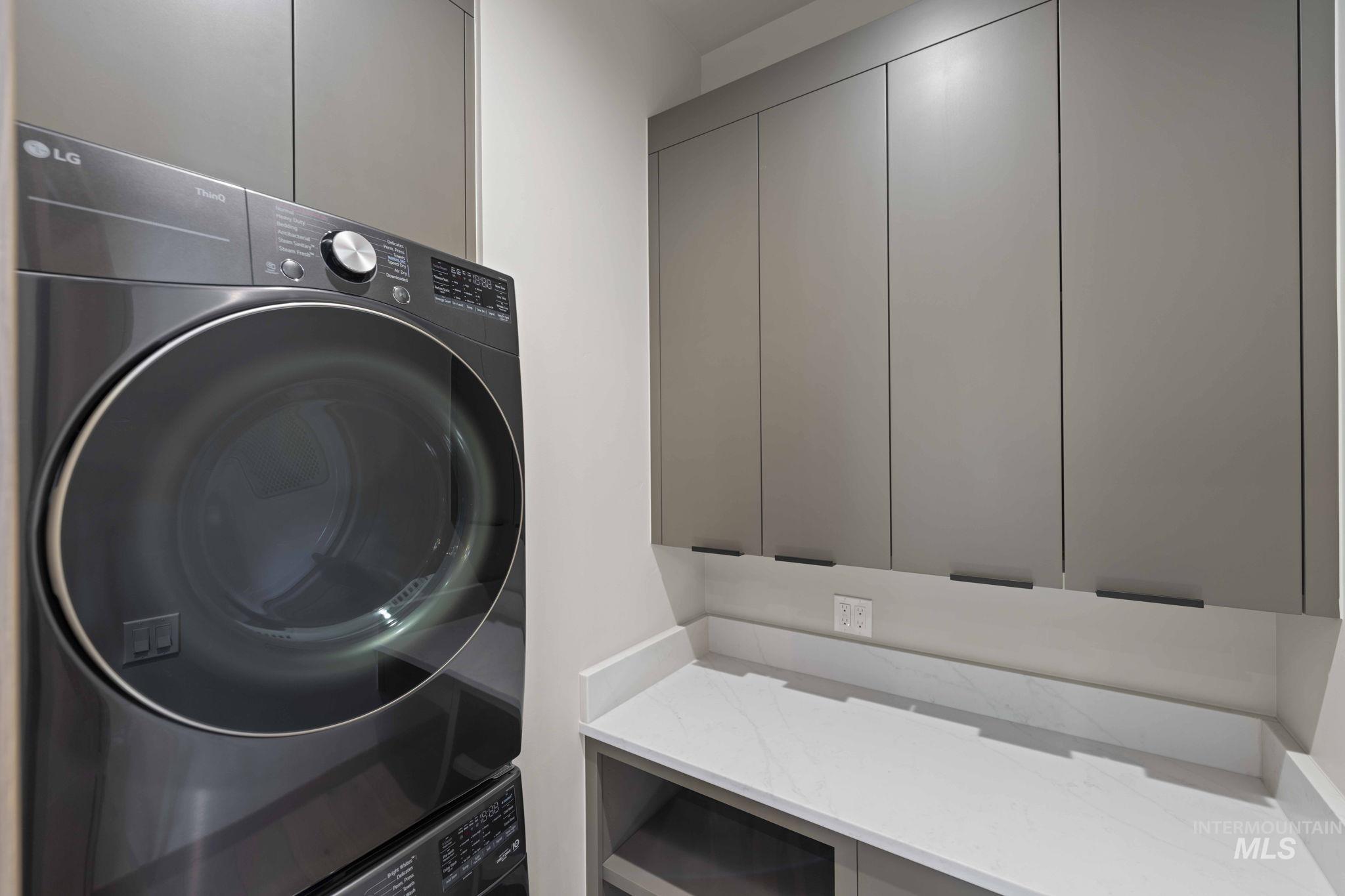 Laundry area featuring stacked washer / drying machine and cabinet space