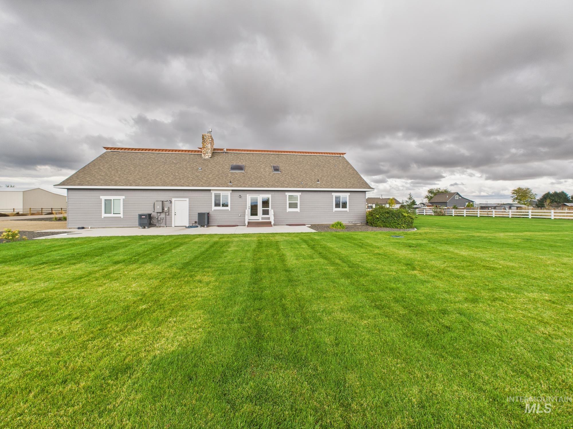 Back of house with a patio area, roof with shingles, and a chimney