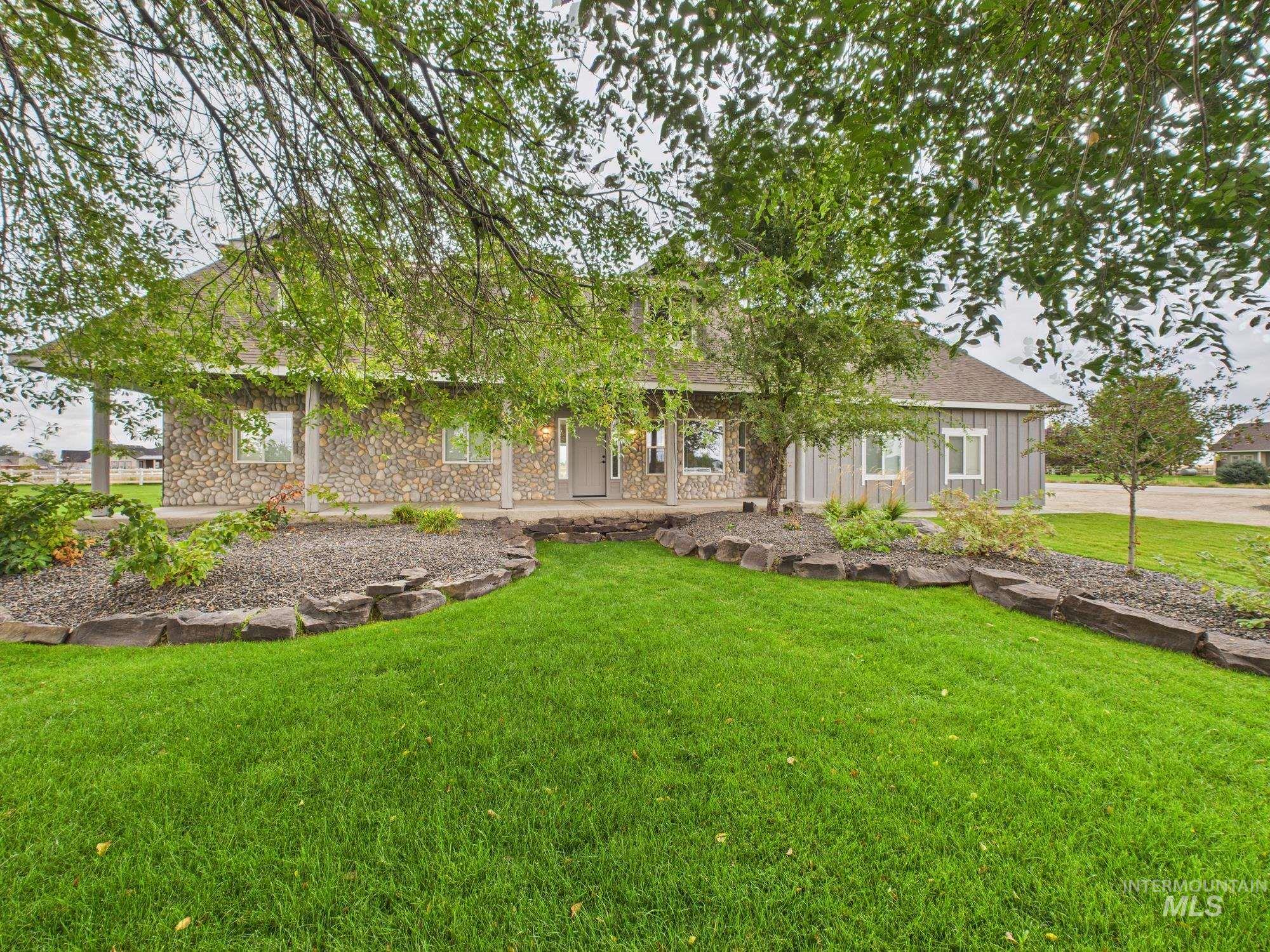 View of front of home with a front yard, a porch, stone siding, and board and batten siding