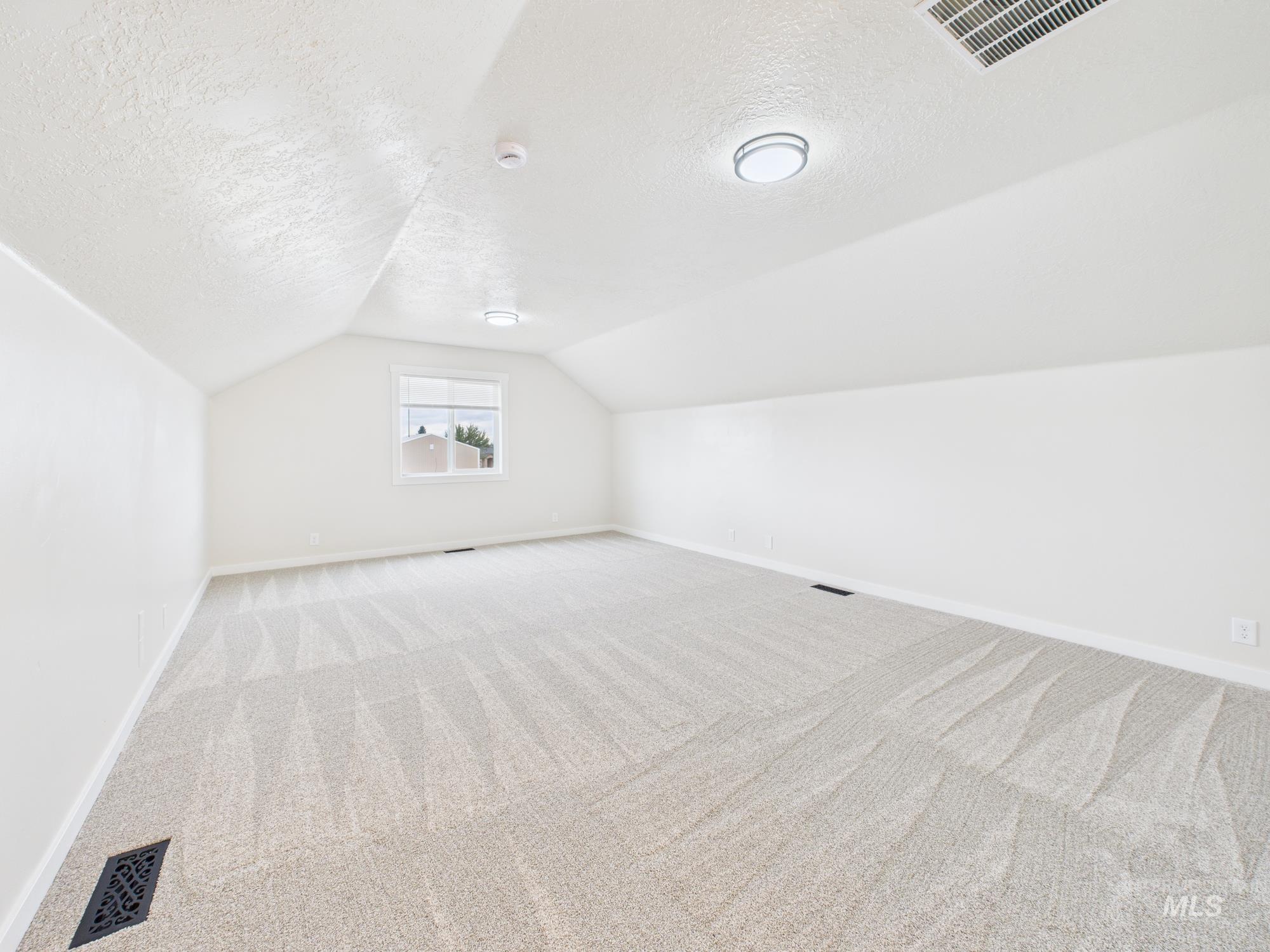 Bonus room with carpet floors, a textured ceiling, and vaulted ceiling