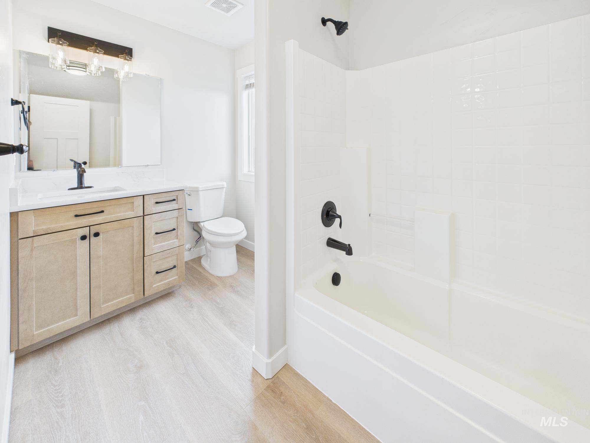 Bathroom with tub / shower combination, vanity, and light wood finished floors