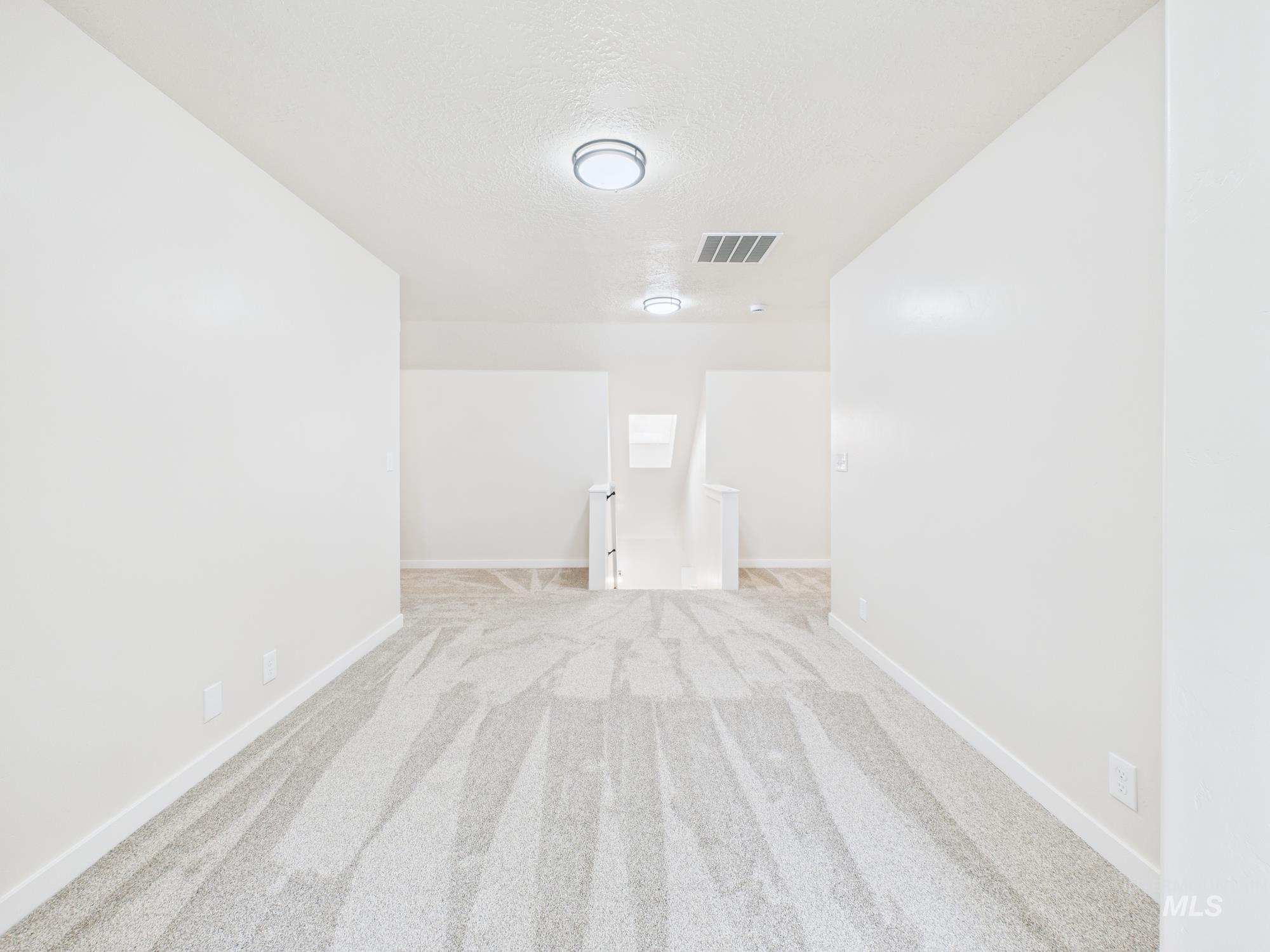 Spare room featuring light colored carpet and a textured ceiling