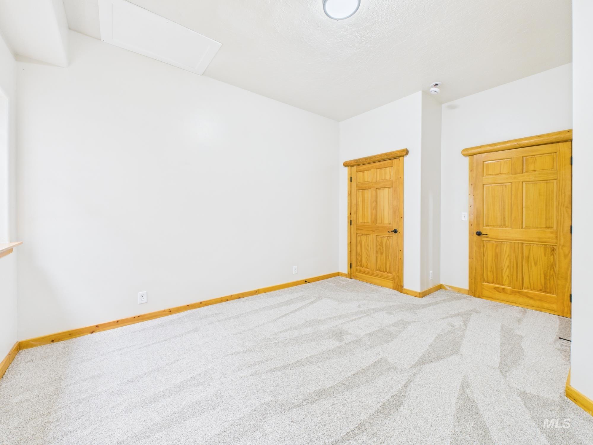 Unfurnished bedroom featuring attic access and light carpet