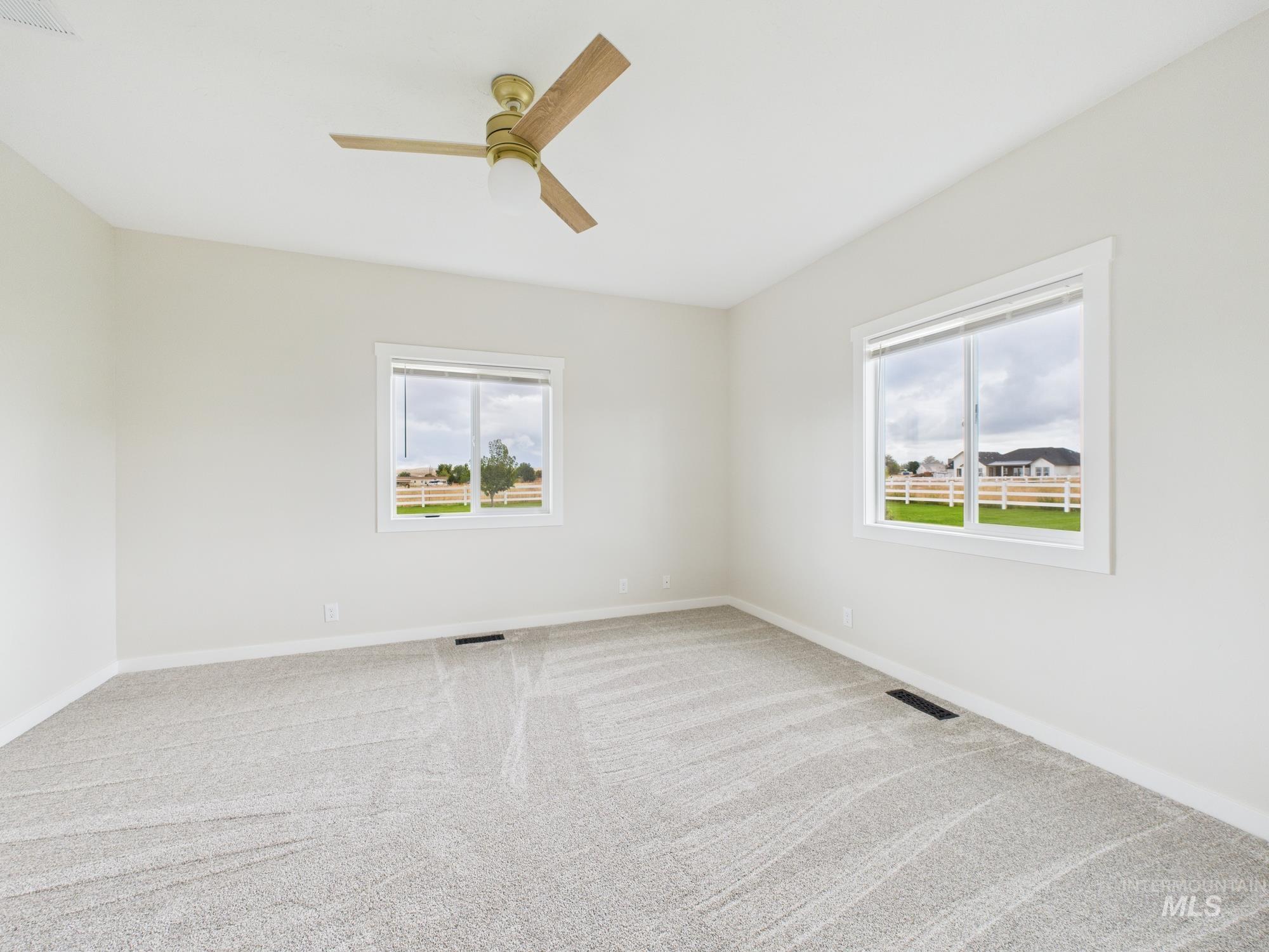 Carpeted empty room with plenty of natural light and a ceiling fan