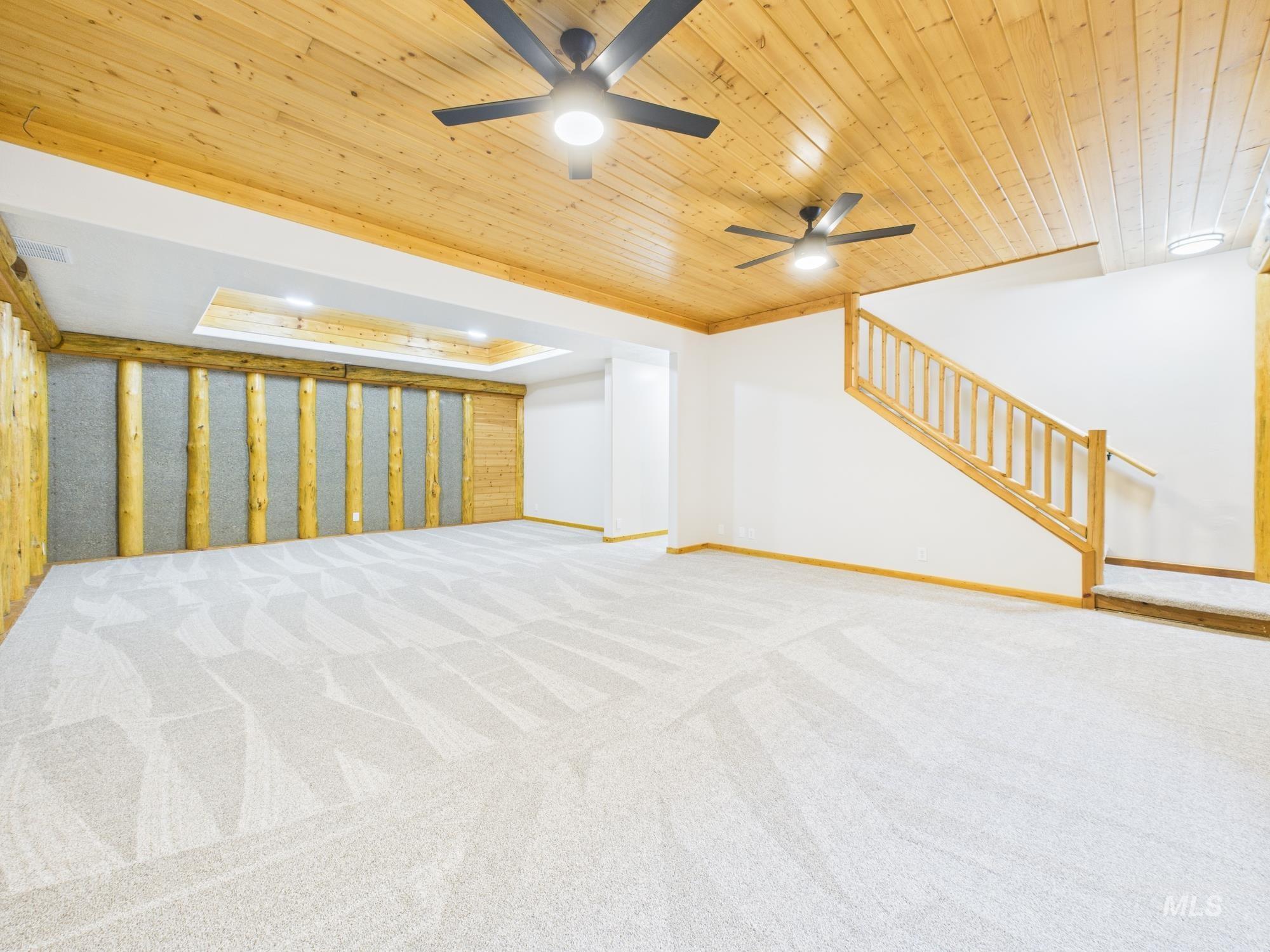 Unfurnished living room with stairway, light carpet, wooden ceiling, and a ceiling fan