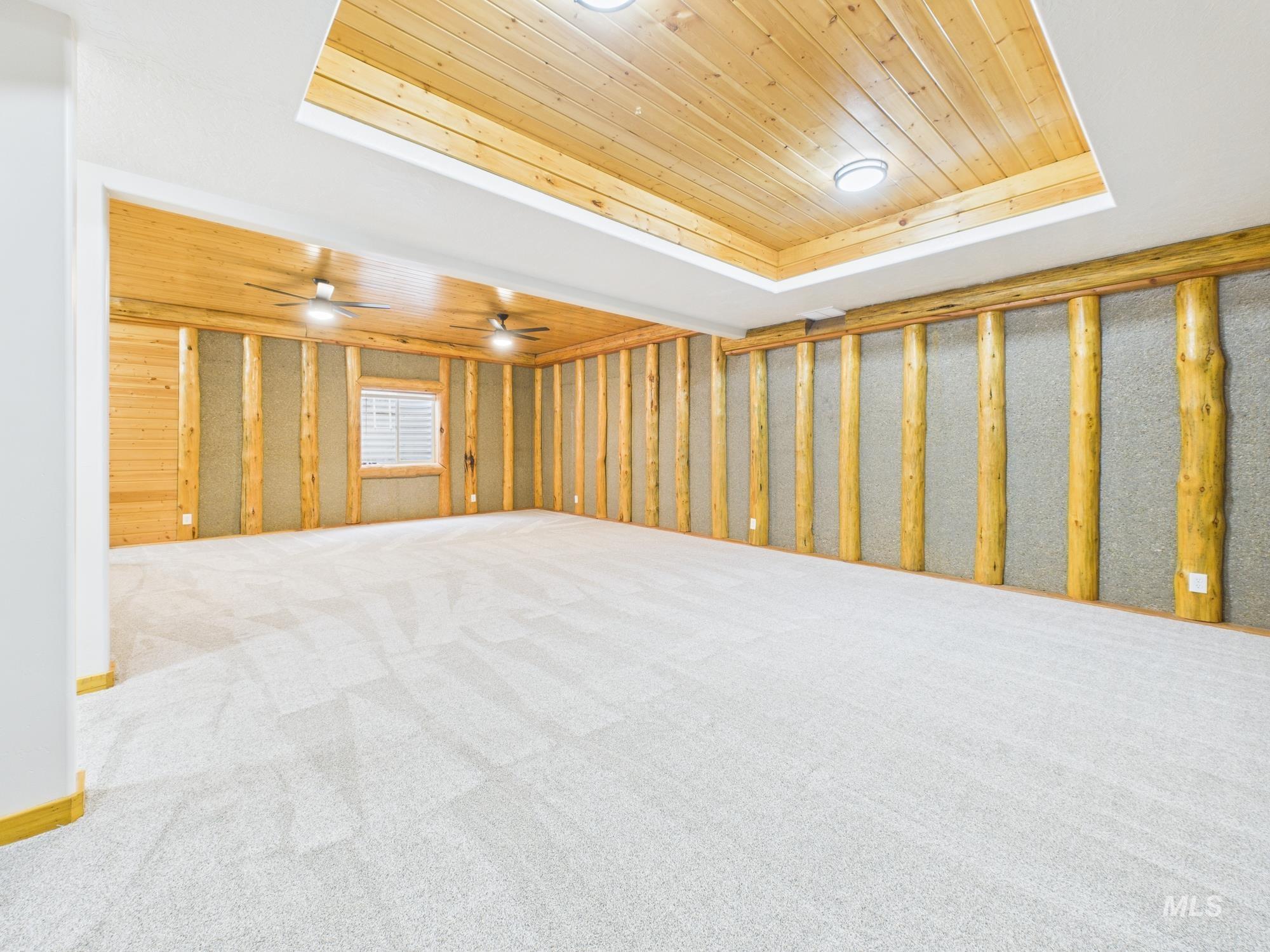 Unfurnished room featuring wooden ceiling, a raised ceiling, and light colored carpet