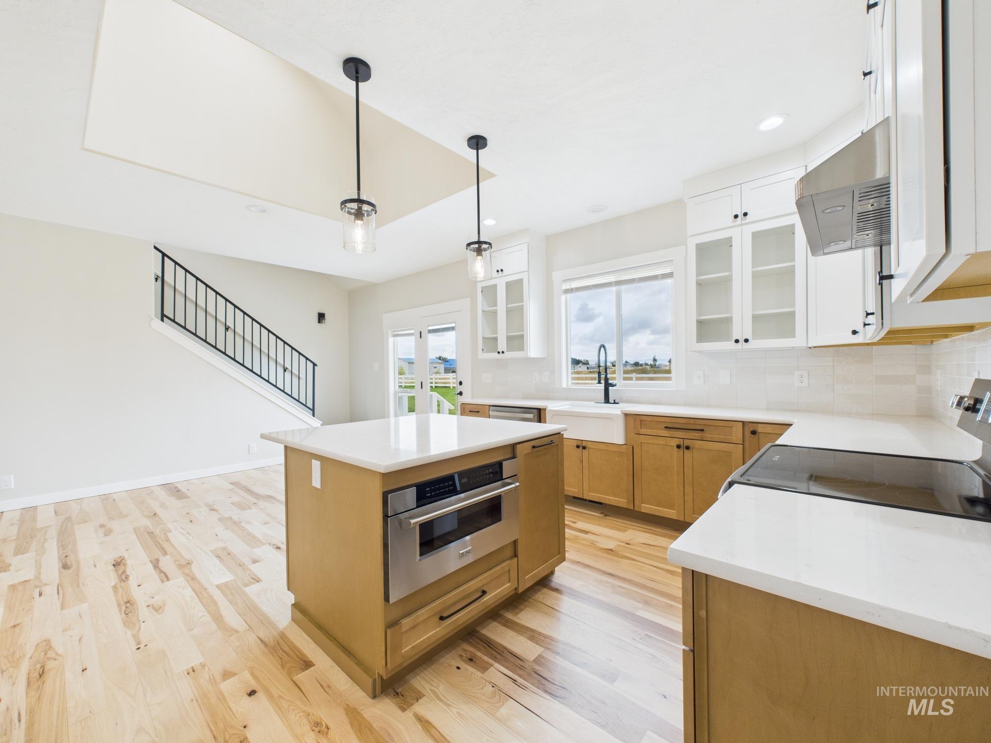 Kitchen featuring glass insert cabinets, backsplash, light wood-style flooring, a center island, and electric range