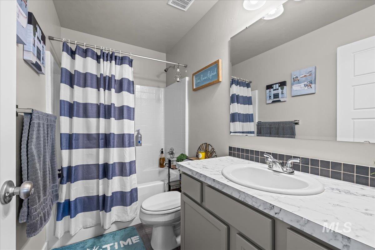 Bathroom featuring shower / bath combo with shower curtain and vanity