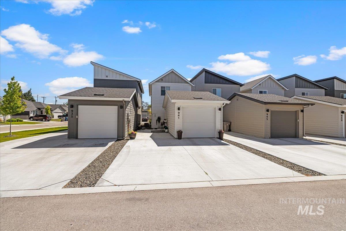 View of front of property featuring board and batten siding, roof with shingles, a residential view, and driveway