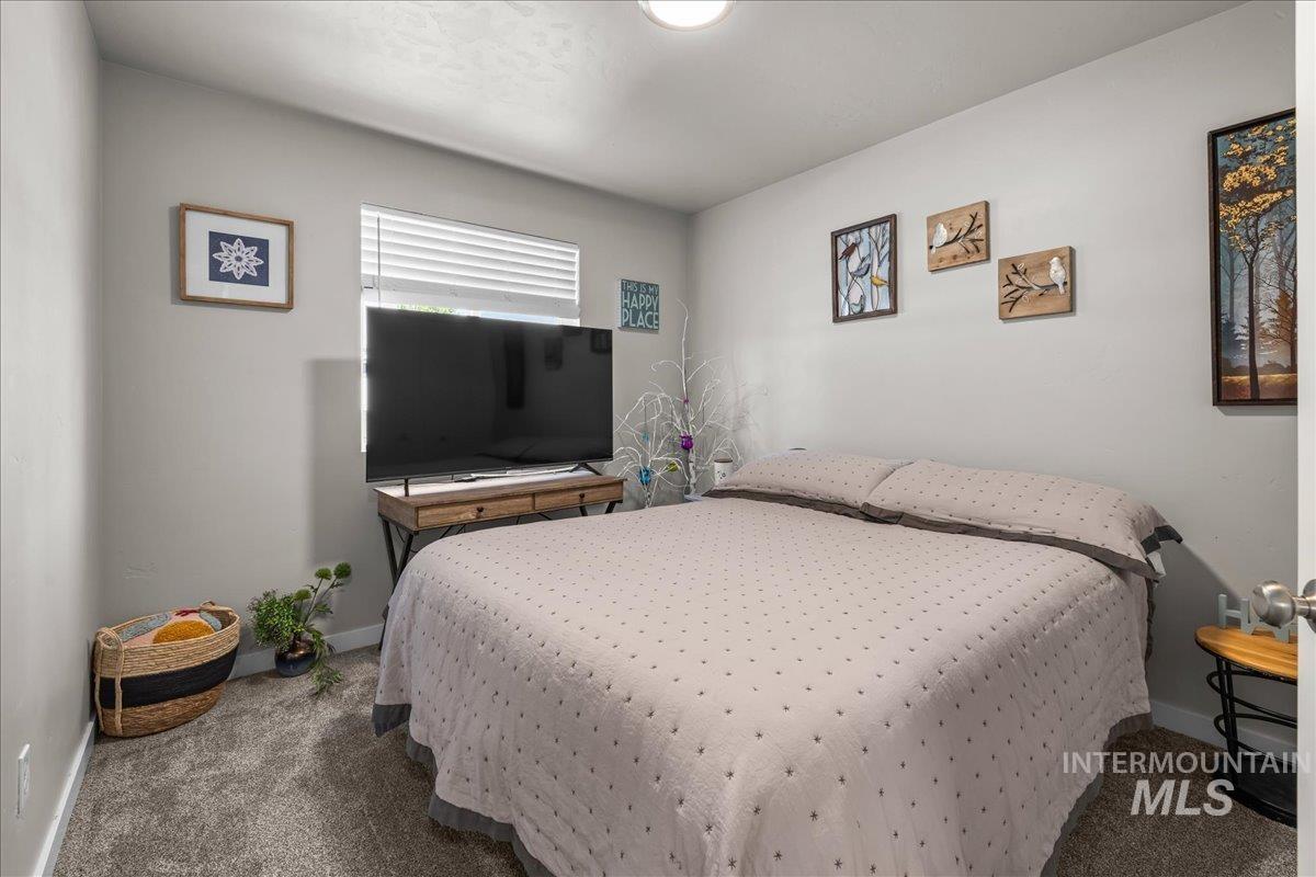 Bedroom featuring dark colored carpet and baseboards