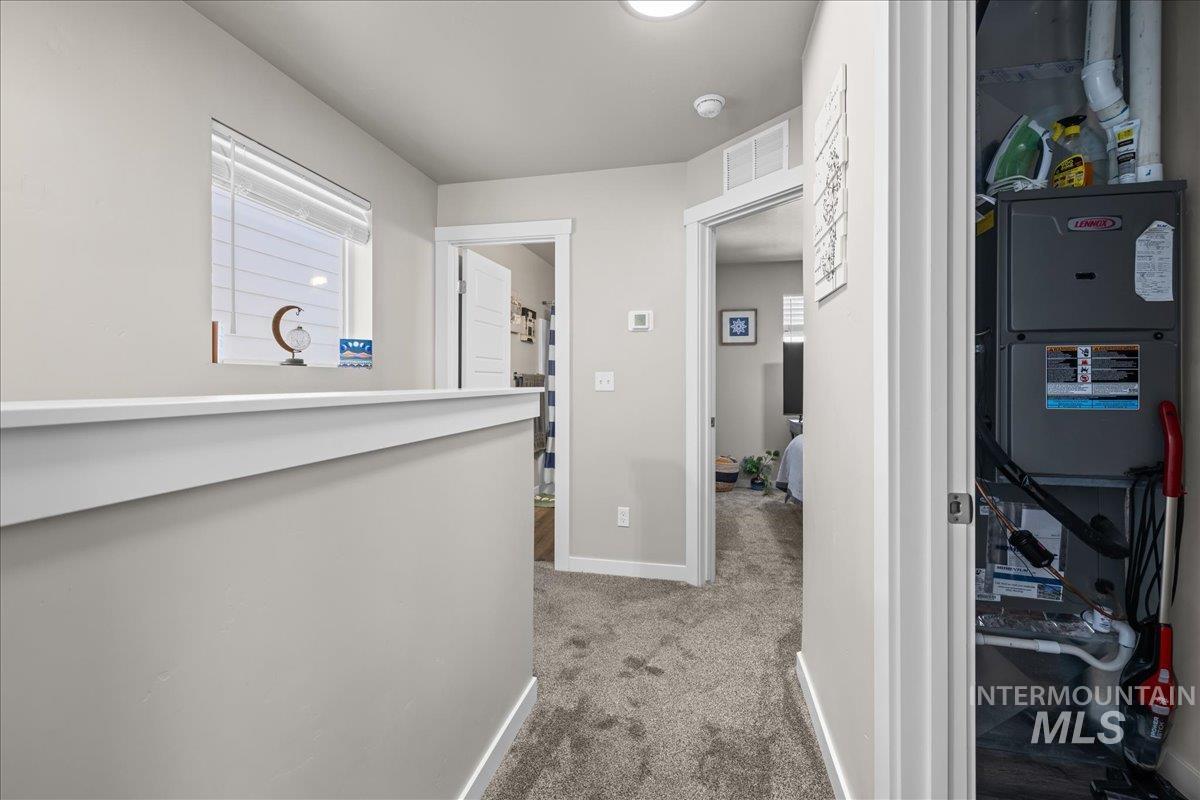Hallway featuring light colored carpet and heating unit