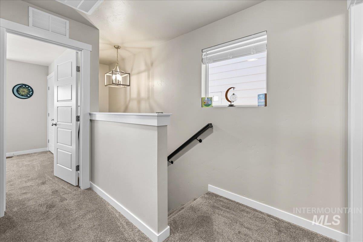 Staircase with carpet floors and a chandelier