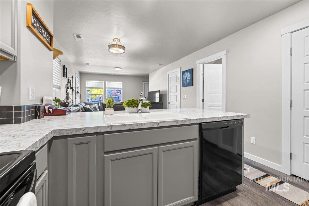 Kitchen with light countertops, black appliances, open floor plan, and a peninsula