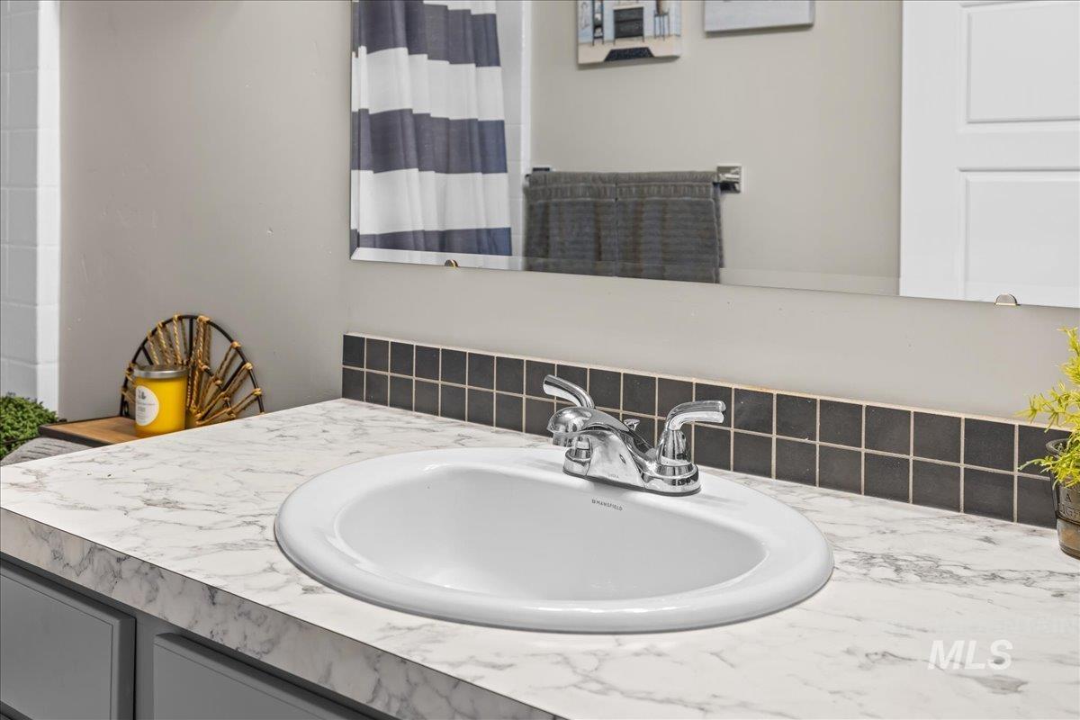 Bathroom view of vanity, a shower with shower curtain, and tasteful backsplash