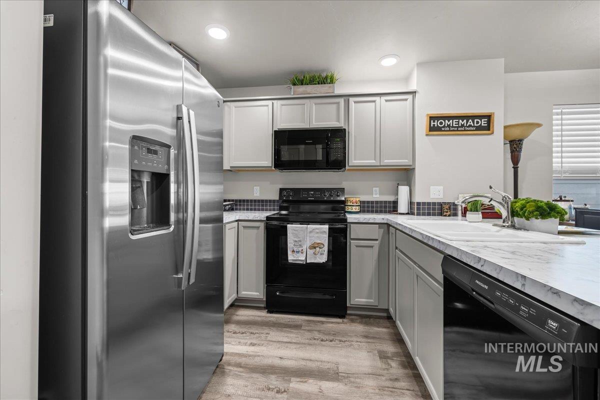 Kitchen with black appliances, light countertops, gray cabinets, light wood finished floors, and recessed lighting