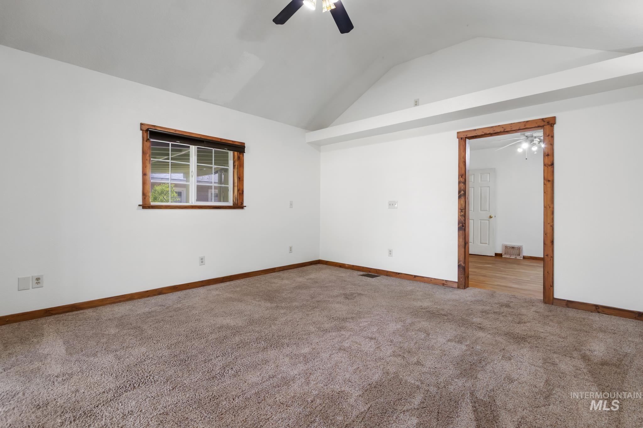 Carpeted room featuring a vaulted ceiling and a ceiling fan