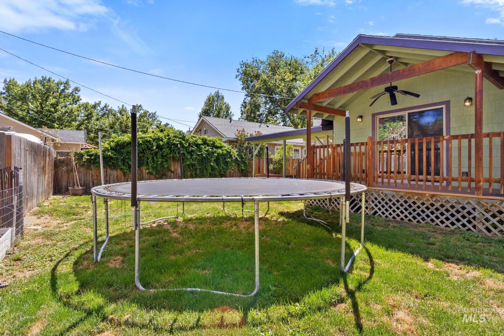 Spacious backyard featuring a grass lawn, privacy fencing, and a built-in deck with wood railings