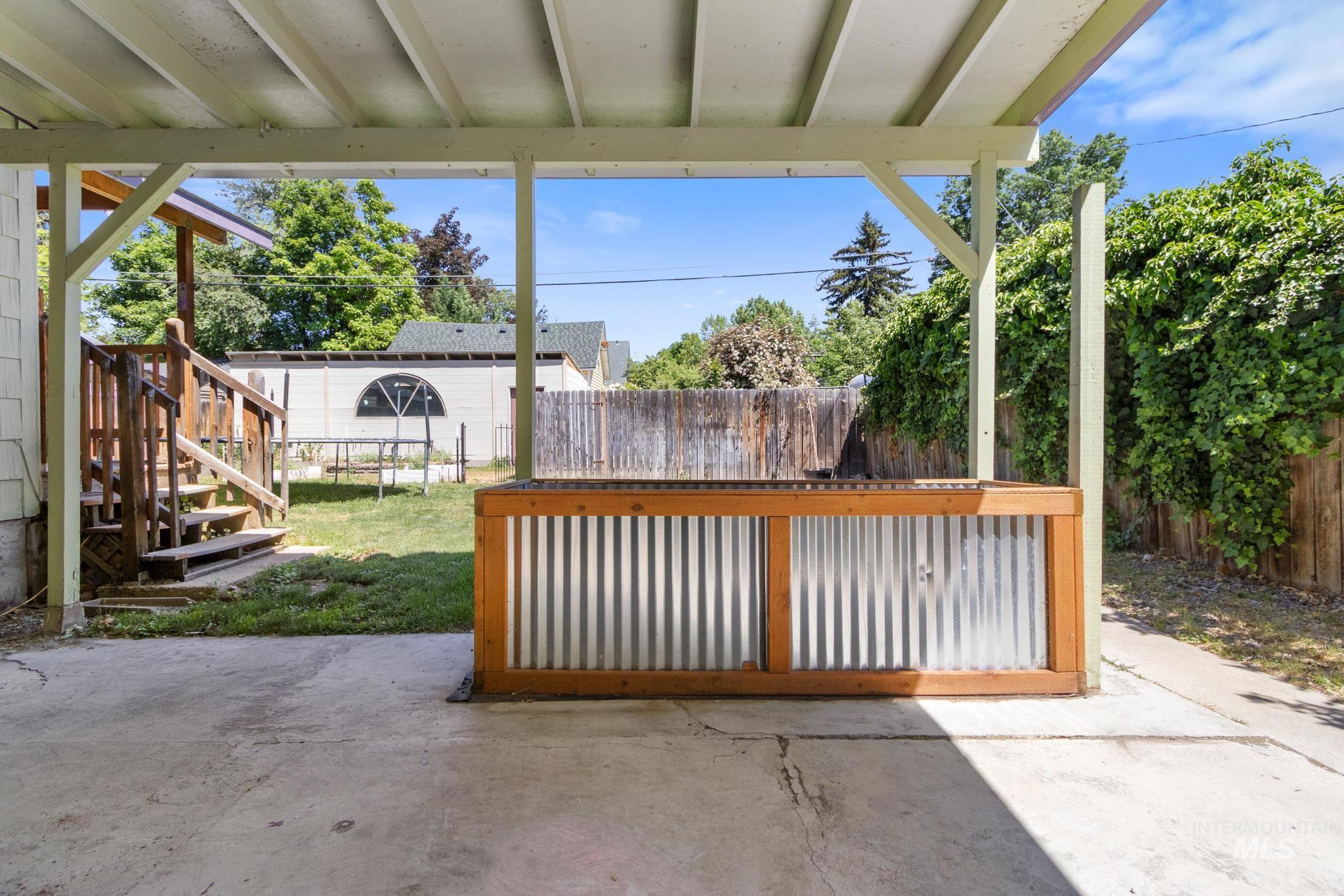 Covered patio with a concrete surface, featuring a built-in corrugated metal and wood-frame bar