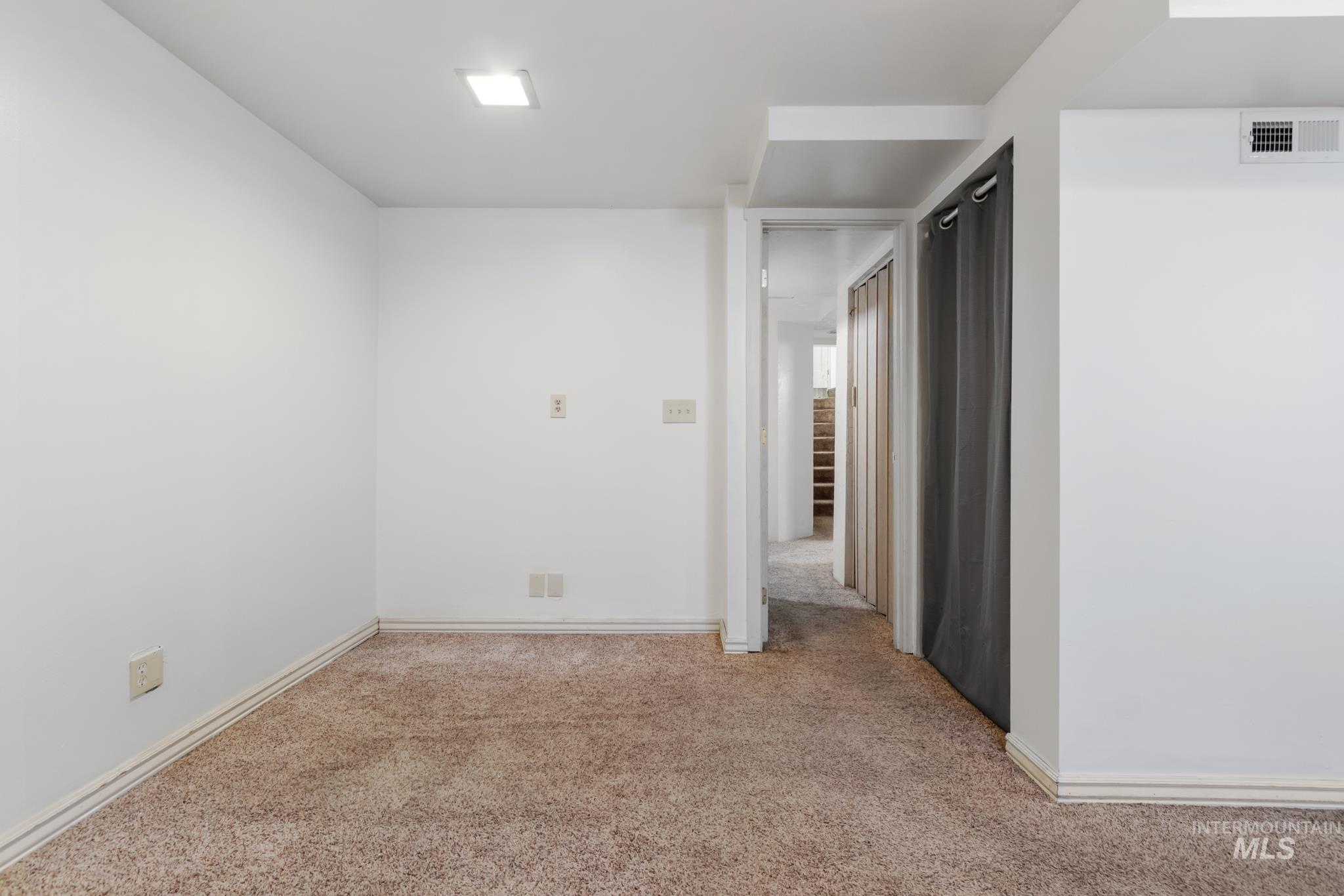 Carpeted interior space featuring white walls and baseboards