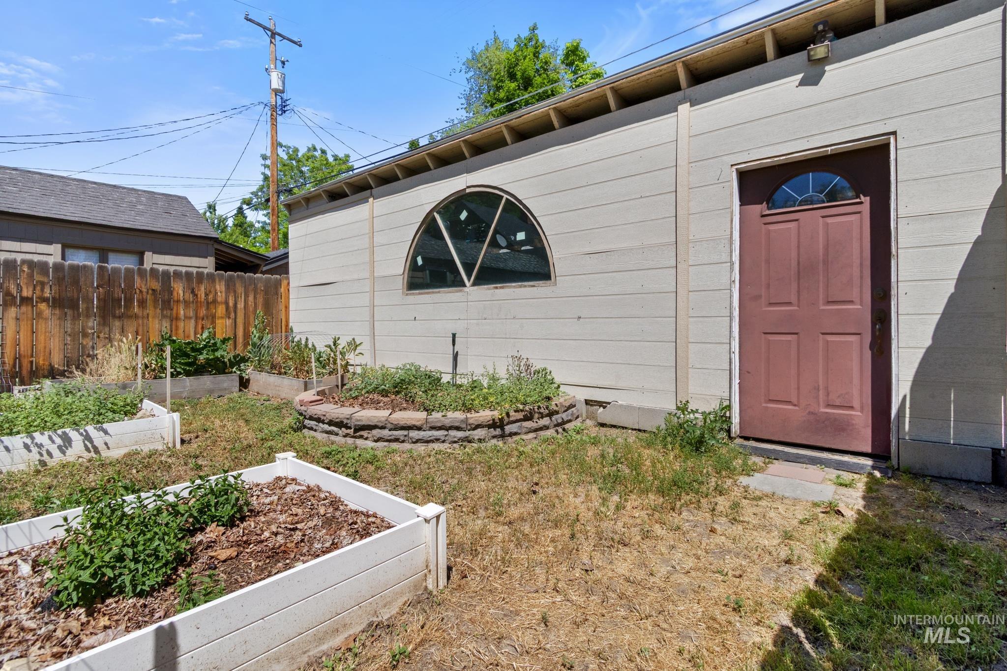 Exterior storage building featuring a half-round window, a paneled entry door with an arched glass insert, and exposed eaves