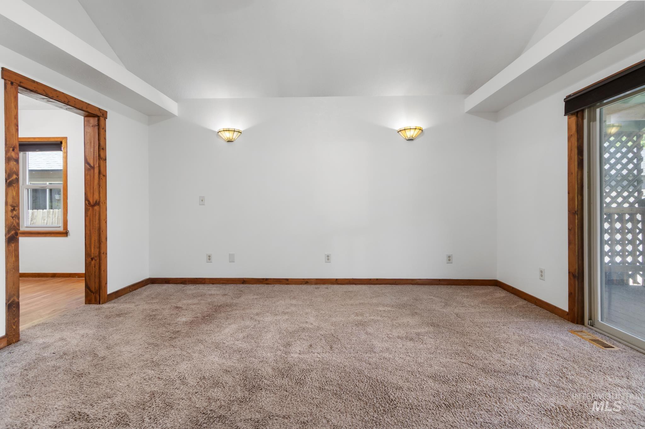 Carpeted interior space featuring white walls and a vaulted ceiling