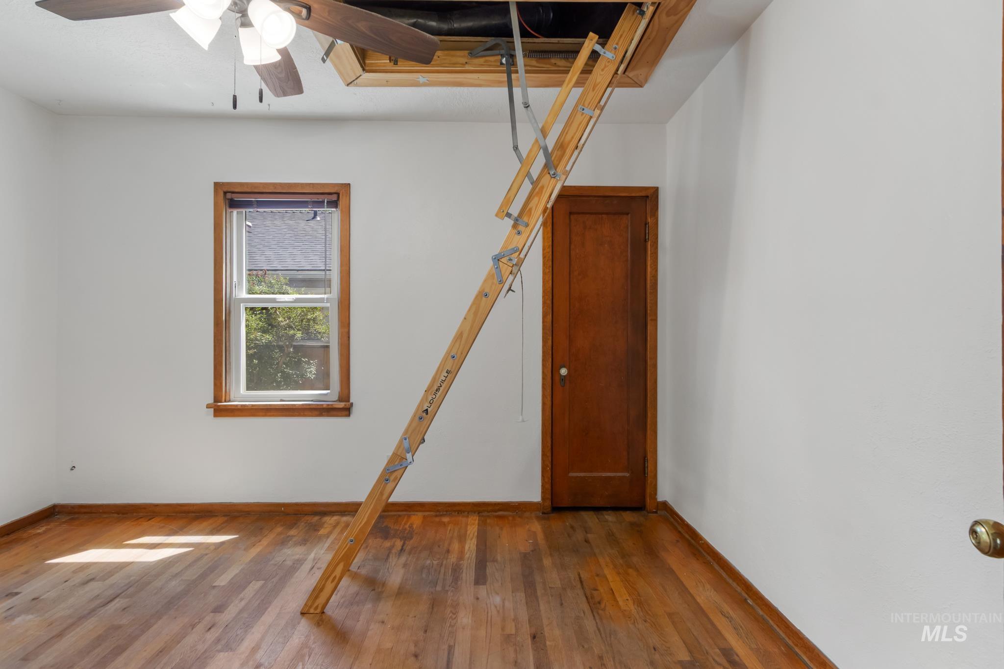 Room featuring wood-finish flooring, a wood-trimmed window, and a wooden door
