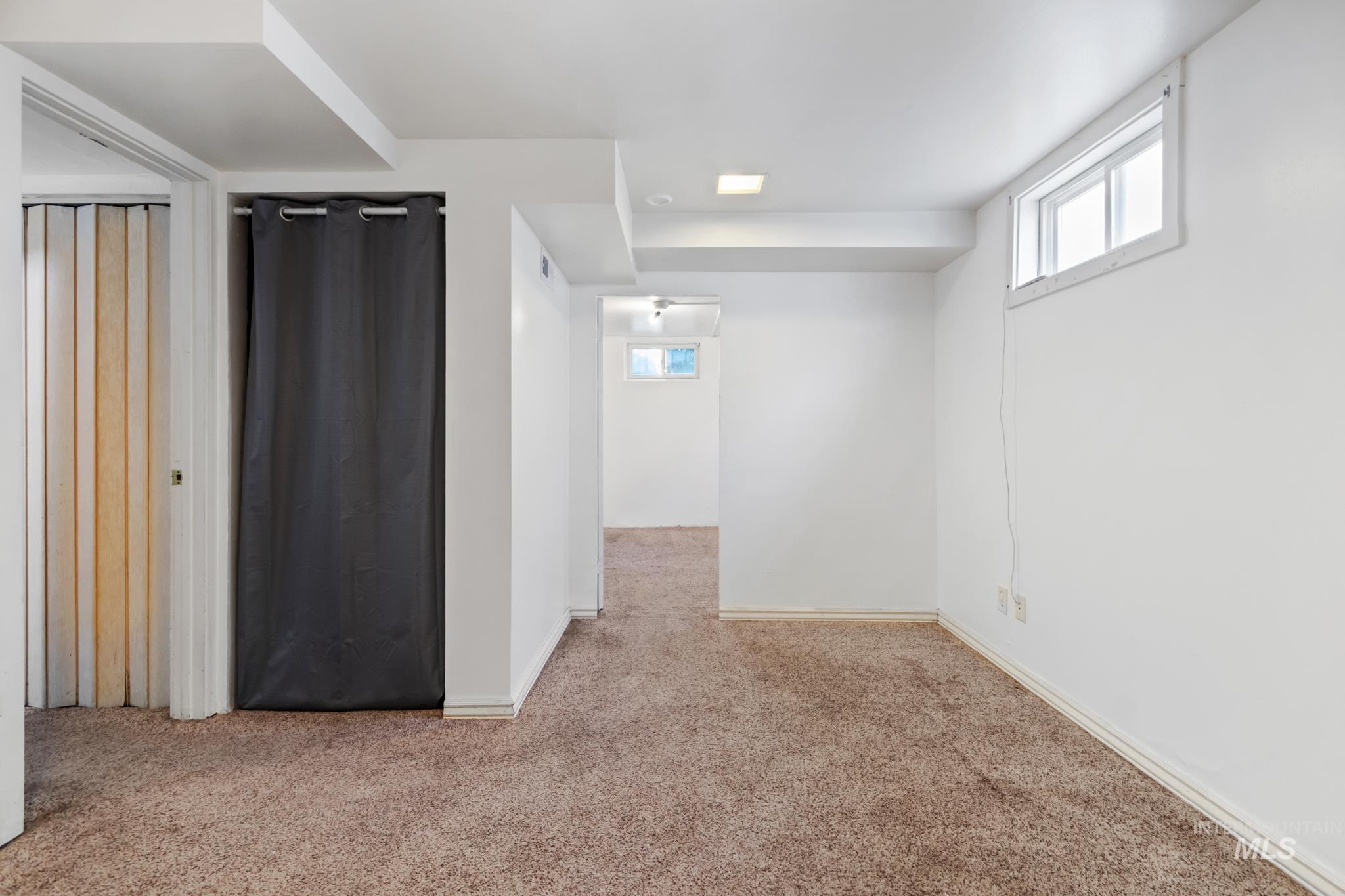 Carpeted room with white walls, recessed lighting, and an egress window