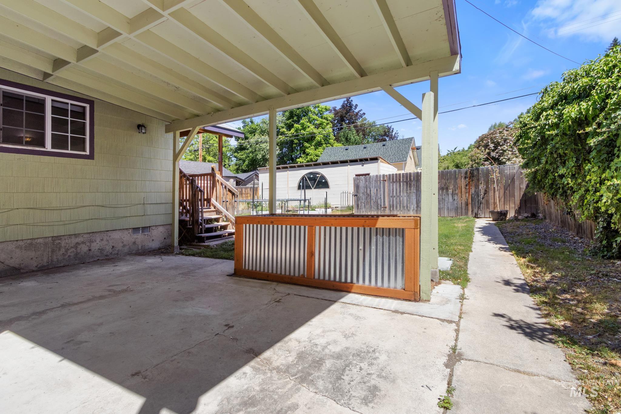 Covered concrete patio area with a wood-frame and corrugated metal planter box