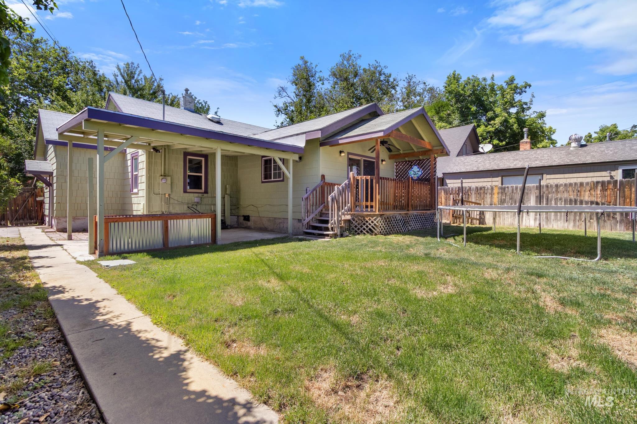 Rear exterior featuring a covered patio, wood deck, and a grass lawn