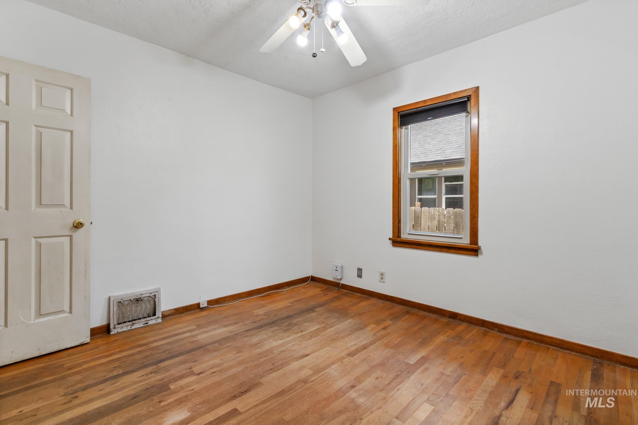 Interior room featuring wood-finish flooring, white walls, and a multi-pane window with wood trim