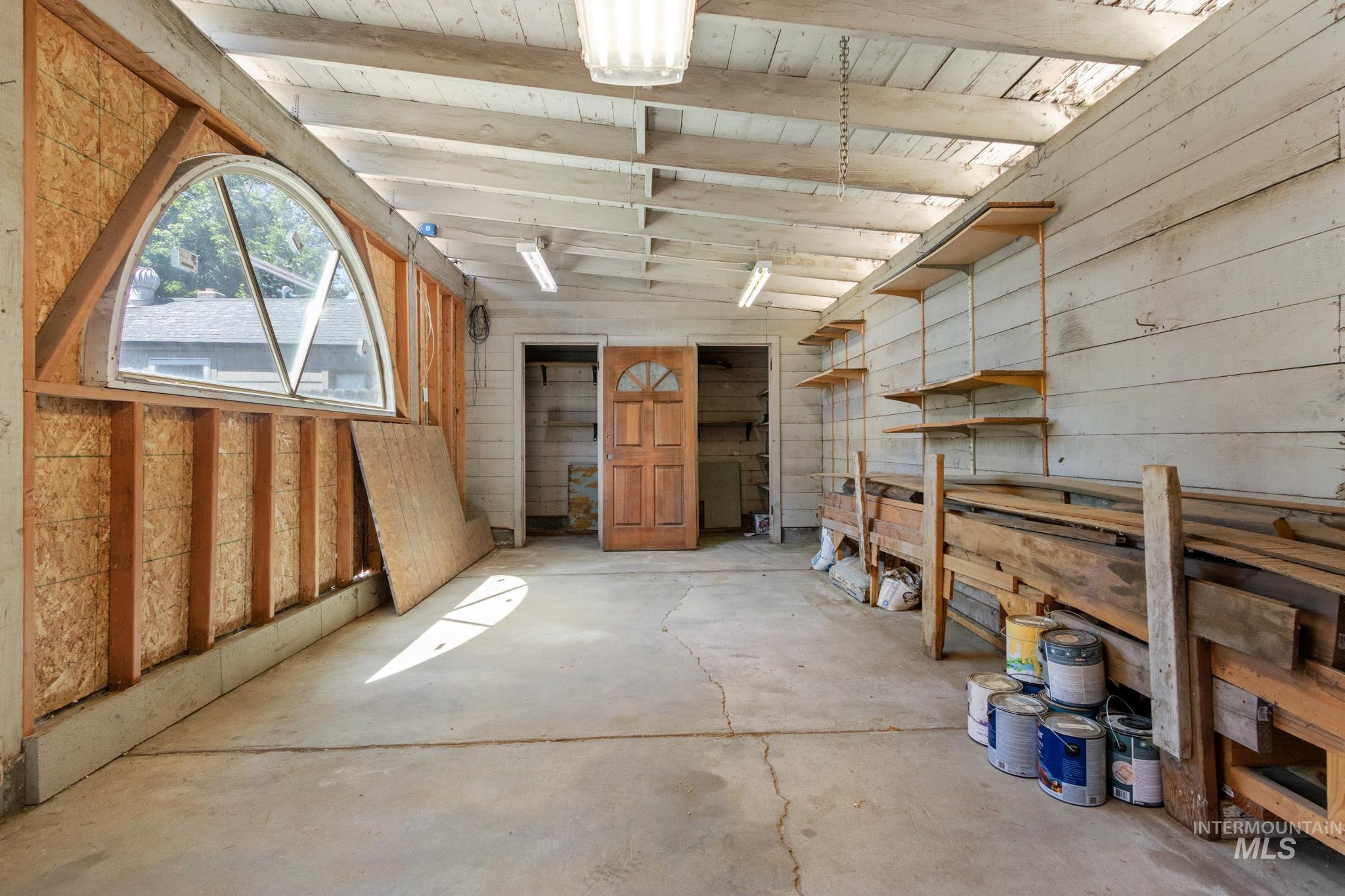 Concrete flooring with exposed ceiling beams and fluorescent lighting fixtures