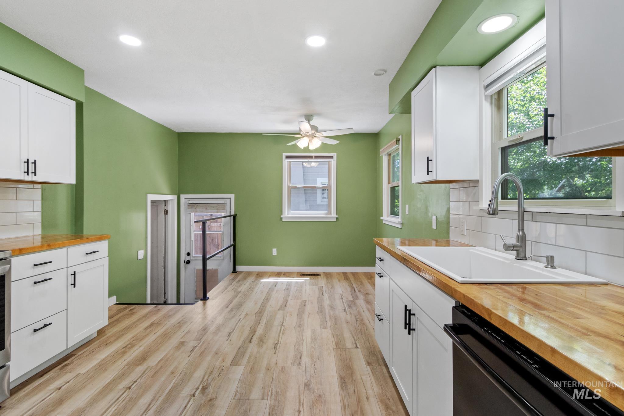 Kitchen featuring white cabinetry with black hardware, wood-finish countertops, and a white subway tile backsplash