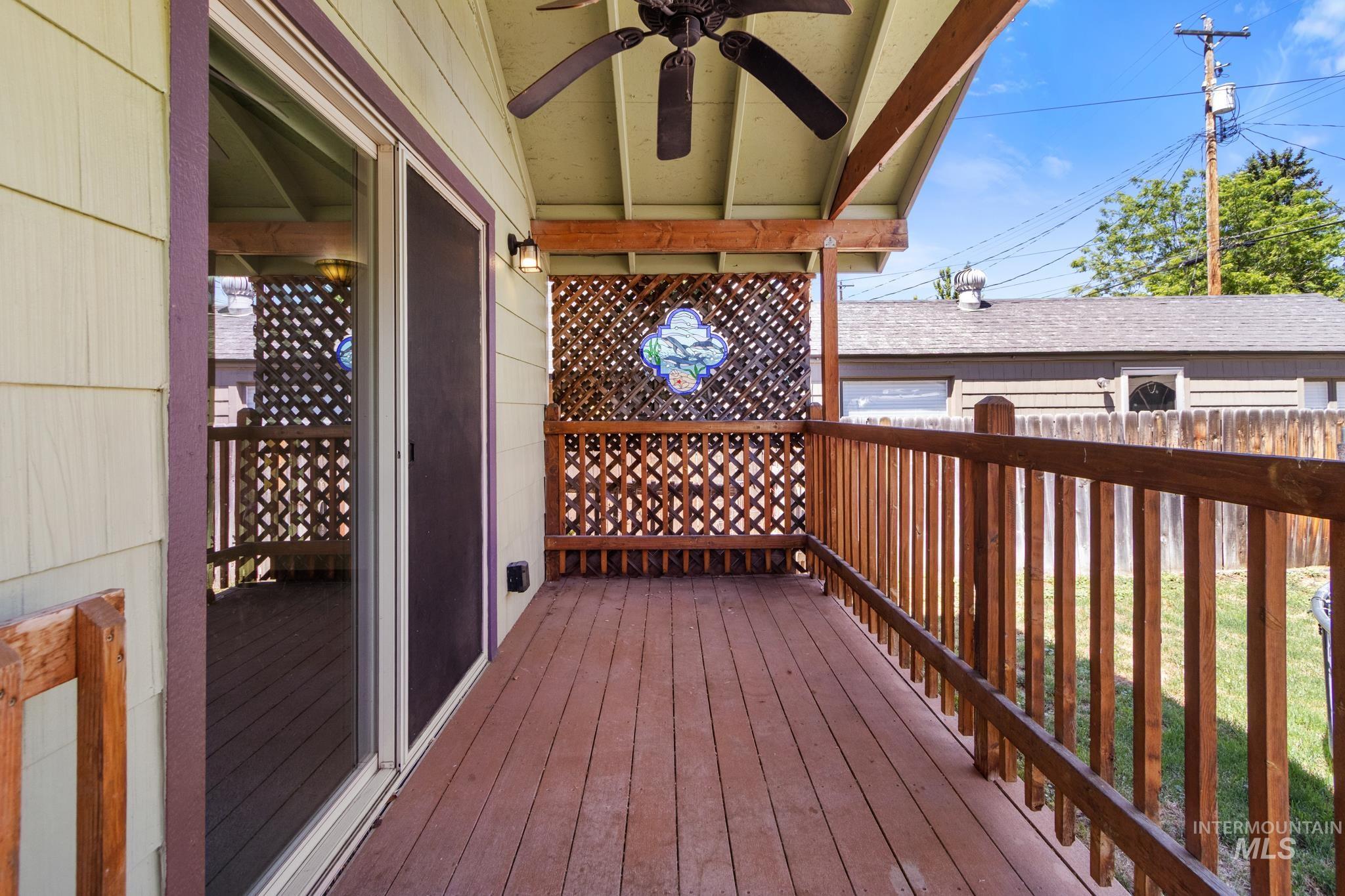 Expansive covered deck featuring wood plank flooring and wood railings