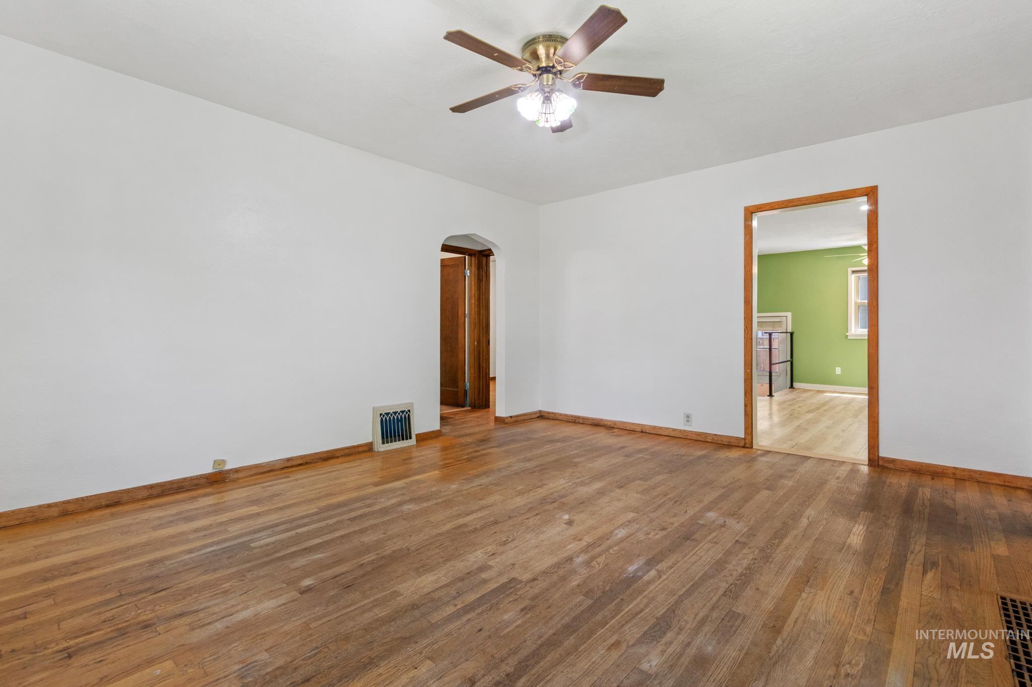 Hardwood flooring throughout, white walls, and a ceiling fan with integrated lighting