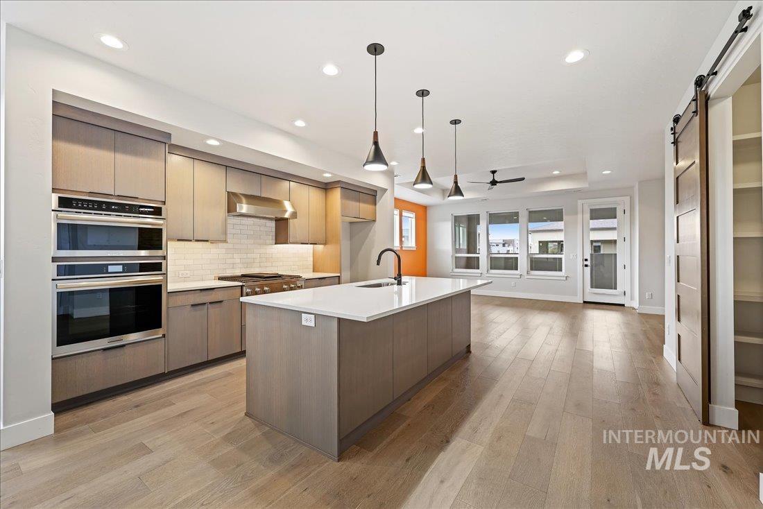 Kitchen featuring a barn door, modern cabinets, backsplash, pendant lighting, and recessed lighting