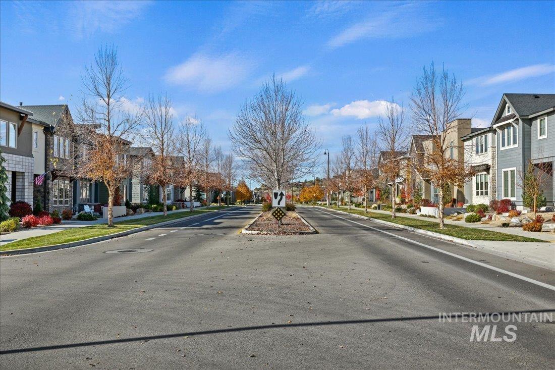 View of asphalt street with sidewalks, curbs, a residential view, and street lights